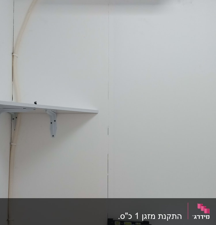 מזגן מותקן על קיר עם צינור חיבור לבן